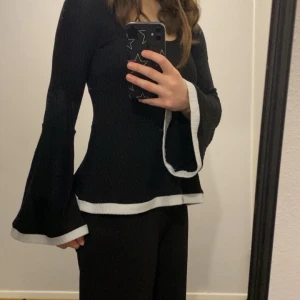 Svart ribbad topp från Uniqlo - Säljer en snygg svart ribbad topp från Uniqlo. Toppen har långa ärmar och en peplum-design som ger en fin siluett. Perfekt för både vardag och fest!