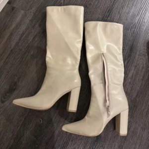 Beige stövlar från Bianca - Snygga beige stövlar från Bianca med dragkedja på sidan och spetsig tå. Perfekta för att ge en stilren touch till din outfit.