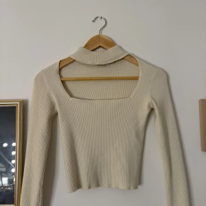 Beige ribbad polotopp - Använd 1 gång. Snygg beige ribbad polotopp med långa ärmar. Perfekt för en stilren look och passar bra till både jeans och kjol. Den har en elegant fyrkantig halsringning som ger en modern touch.