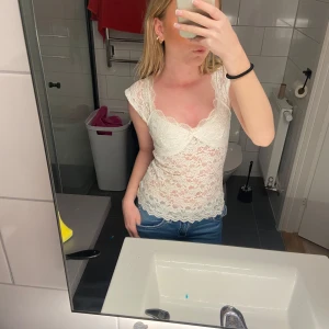 Vit spetsblus - Säljer en söt vit spetsblus med korta ärmar och v-ringad design. Perfekt för sommarens varma dagar. Blusen har en fin spetsdetalj som ger en romantisk känsla. Har använt den en gång. Pris kan diskuteras💖
