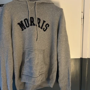 Grå hoodie från Morris - Säljer en stilren grå hoodie från Morris. Liten defekt mellan snörerna (Bild 4) men ingenting man lägger märke till när tröjan används. Perfekt för en avslappnad stil.