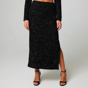 Svart glittrig lågmidjad långkjol - Snygg svart långkjol med glittrigt mönster och en slits på sidan. Perfekt för att ge en extra touch till din outfit, exempel till nyår eller en utekväll! Kjolen har en tight passform som framhäver figuren. Kjolen är helt ny från bikbok i storlek S. Original pris 400kr. Säljer pga hittat en ny outfit till nyår.