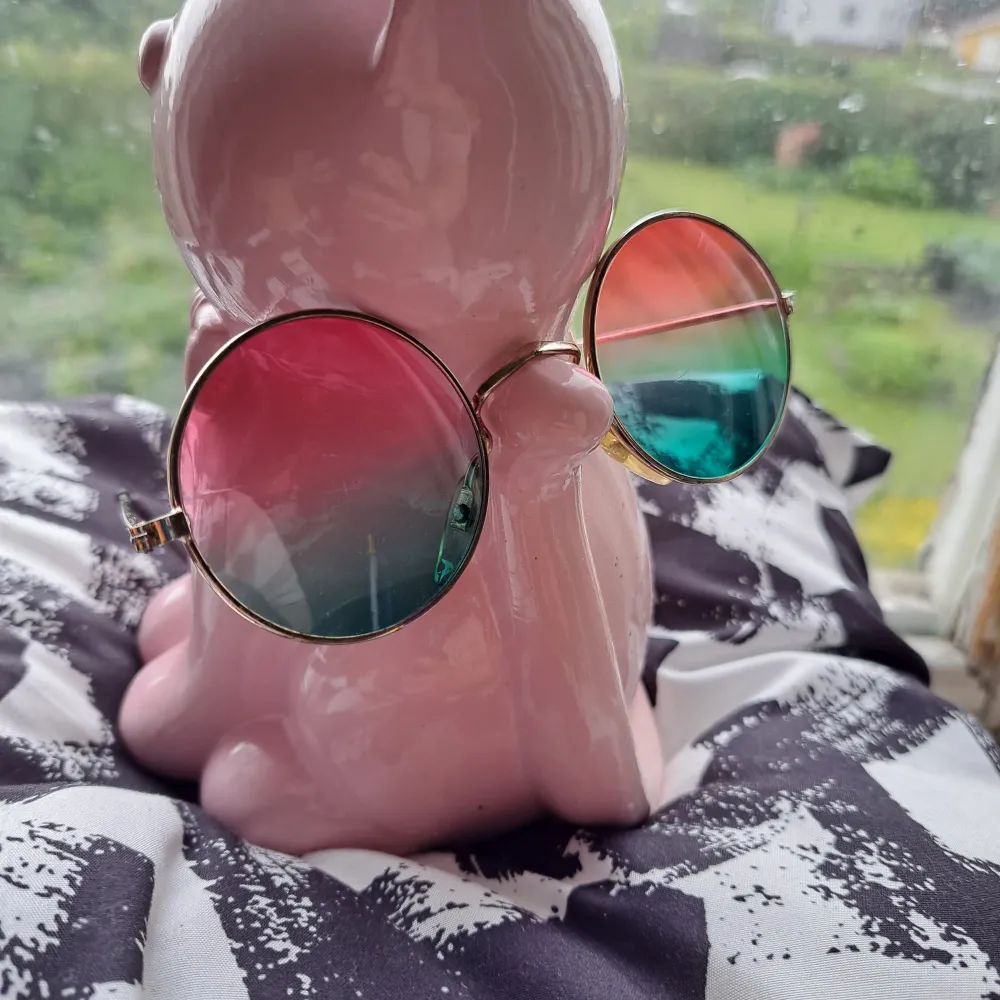Snygga runda solglasögon med färgskiftande glas i rosa och grönt. Glasögonen har en tunn guldfärgad metallram som ger en retro känsla. Perfekta för att ge din stil en unik touch. Har små repor i glaser, men det syns inte när du bär dem.. Asusteet.