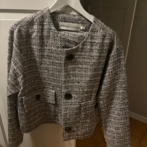 Kofta från Inwear - En väldigt stilren kofta med knappar och två fickor framtill. Ordinarie pris 1700kr. Den har en klassisk rund hals och är perfekt för en stilren look. Passar bra till både vardag och mer uppklädda tillfällen. Gör ett uttryck av ”old money stil” väldigt elegant.