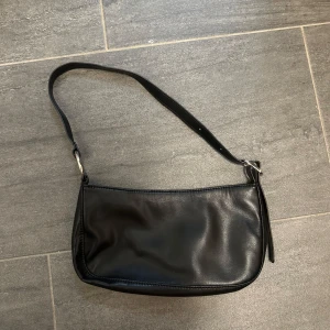 Svart axelväska i skinn - Snygg och stilren svart axelväska i skinn med justerbar axelrem och silverfärgade detaljer. Jätte söt väska💗