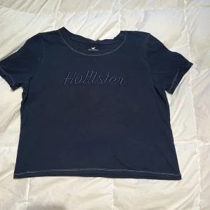 Mörkblå t-shirt från Hollister - Säljer en mörkblå t-shirt från Hollister med broderad logga på framsidan. T-shirten har korta ärmar. 