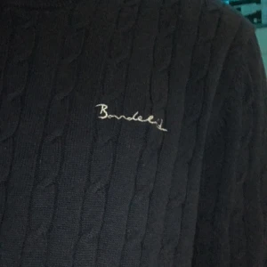 Svart stickad tröja från Bondelid - Säljer en stilren svart stickad tröja från Bondelid. Tröjan har ett diskret kabelstickat mönster och långärmade ärmar. Perfekt för en klassisk look.