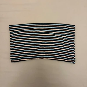 Randig tubtopp i ribbat material - Snygg randig tubtopp i ribbat material med färgerna svart, vit och blå. 