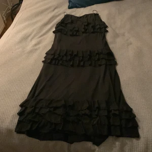 Svart lång kjol från Nelly - Elegant svart lång kjol från Nelly med volangdetaljer. Kjolen var lite för lång för mig och har använt en gång. Perfekt för speciella tillfällen.
