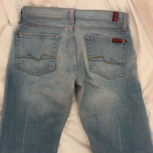 Ljusblå bootcut jeans från 7 for All Mankind - Säljer ett par ljusblå bootcut jeans från 7 for All Mankind. De har en klassisk femficksdesign och är lågmidjade. Perfekta för en avslappnad stil med en snygg passform. Innerbenslängd: 85 och midja: 37 cm