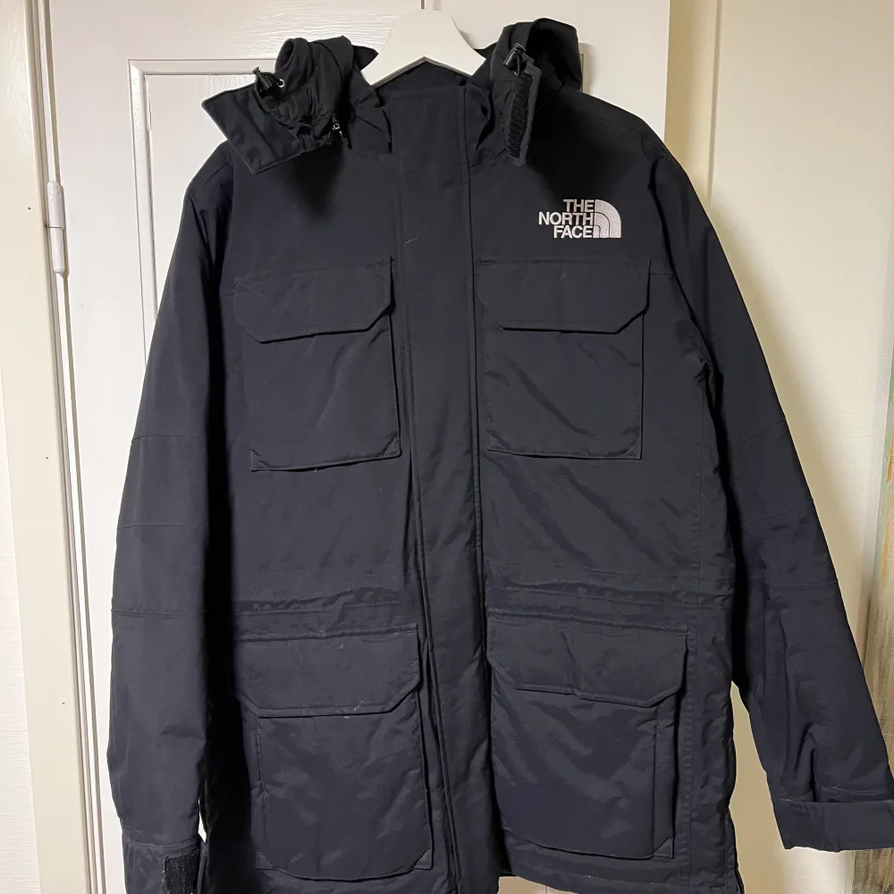 Säljer en svart jacka från The North Face med huva och flera praktiska fickor. Jackan har en dragkedja framtill och är perfekt för kyligare väder. Den är långärmad och har en stilren design med logotyp på bröstet och ryggen.. Takit.