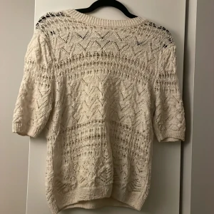 Vit stickad tröja med spetsdetaljer - Säljer en beige stickad tröja från zara med vackra spetsdetaljer. Tröjan har trekvartsärmar och ett fint mönster som ger en bohemisk känsla. Perfekt för lager-på-lager under kyligare dagar. Tröjan är i fint skick och går inte att få tag på längre