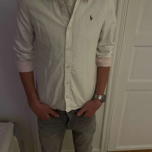  Vit Ralph Lauren Skjorta - Säljer en stilren vit skjorta från Ralph Lauren med väldigt fint skick. Han på bilden är 170 cm och skjortan sitter perfekt i passformen på honom. Vid frågor eller intresse så är det bara att kontakta!