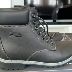 Svarta boots från Fila - Snygga svarta boots från Fila med snörning och robust sula. Perfekta för höst och vinter med en stilren design och bekväm passform.