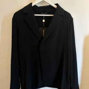 Svart kavaj från Manière De Voir - Elegant svart kavaj från Manière De Voir med klassisk krage och långa ärmar. Perfekt för en stilren look. Nypris 1400 aldrig använd, pris 700.