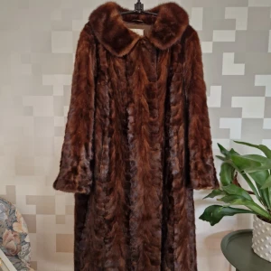 Minkpäls från Pälsman - Elegant brun pälsjacka från Pälsman, perfekt för kalla dagar. Jackan har en klassisk design. Tillverkad i Tranås, den ger en lyxig känsla och stil. Storleken uppskattas ca M, runt 40/42. Nypris på minkpälsar ca 50000-75000:- Köparen betalar frakten. 