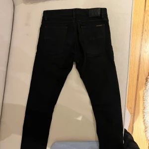 Svarta jeans från Nudie Jeans - Snygga svarta jeans från Nudie Jeans med klassisk femficksdesign och knappgylf. Perfekta för en stilren look. Vet ej modellen på byxorna, därför att ja rensade garderoben 