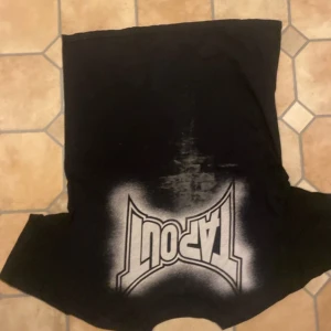 Svart T-shirt från Tapout - Cool svart T-shirt från Tapout med tryck i vitt och grått. Texten 'Hungry will fight to survive' ger en tuff look. Perfekt för dig som gillar en sportig stil.