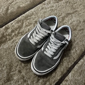 Grå sneakers från Vans - Snygga grå sneakers från Vans i mocka med vita detaljer och snörning. Perfekta för en avslappnad stil.