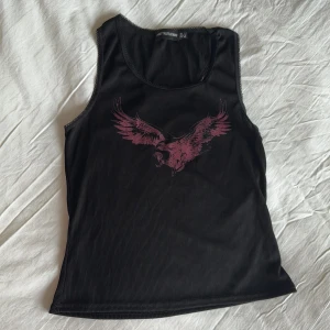 Svart linne med tryck - Racer back topp med rosa fågeltryck på framsidan och spetsdetalj. Strl small.