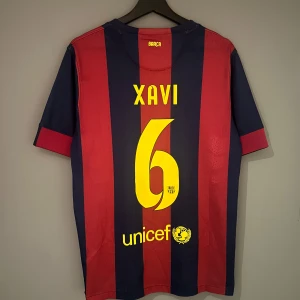 FC Barcelona fotbollströja med Xavi 6 från 2014/15  - Säljer en klassisk FC Barcelona tröja från Nike med Xavi och nummer 6 på ryggen. Tröjan är randig i rött och blått med Qatar Airways som sponsor och klubbens emblem på bröstet. Perfekt för fans av Barca och Xavi! Det är en Replika i storlek Medium den är relativt använd men bra skick