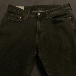 Svarta jeansbyxor - Snygga svarta jeansbyxor med klassisk femficksdesign och knappgylf. Perfekta för en stilren look. Passar till många olika outfits.