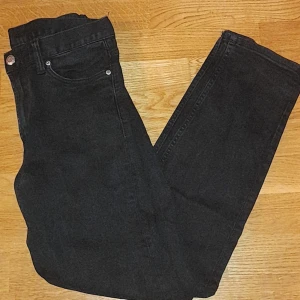 Svarta jeansbyxor - Snygga svarta jeansbyxor med klassisk fyraficksdesign. De har en rak passform och är perfekta för en stilren look. Byxorna har en knapp och dragkedja framtill. Storlek 29/30