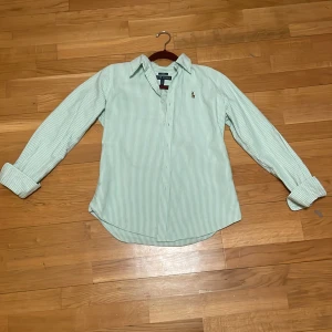 Grön- och vitrandig skjorta från Ralph Lauren - Grön och vit- randig skjorta från Ralph Lauren med broderad logo. Det är slim fit. Säljs pågrund av att den inte passar längre. Övrigt en snygg skjorta som passar till allt pris kan diskuteras. HAR ANDRA FÄRGER⚪️🔵kolla mitt konto.Byten är intressanta.