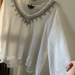 Trekvart tröja - Jätte fin och elegant trrkvartsärmad tröja. Med strass runt halsen och fint lite genomskinligt matrial. Säljer pga för stor. Det står 32/34 men skulle säga 32/38. Den skulle passa många storlekar