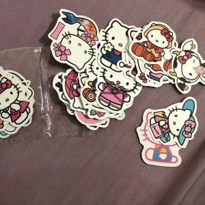 Hello Kitty klistermärken - En samling av färgglada Hello Kitty klistermärken i olika stilar och teman. Perfekt för att dekorera anteckningsböcker, telefoner eller andra personliga föremål. Varje klistermärke har en unik design med den ikoniska Hello Kitty-karaktären.46 sticker