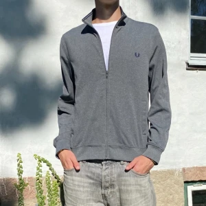 Grå Fred Perry kofta - Skön grå kofta från Fred Perry. Mjuk och varm. Passar till allt. Inga defekter. Liten i passform sitter som en S. Nypris 1500kr