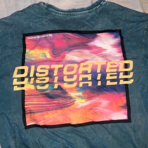 Blå t-shirt med tryck från YOURTURN - Säljer en cool blå t-shirt från YOURTURN med ett färgglatt tryck på baksidan. Framsidan har en liten text i gult. Perfekt för att liva upp ett par jeans