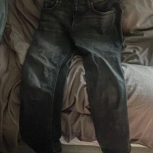 Svarta jeans från Jack & Jones - Säljer ett par svarta jeans från Jack & Jones. De har en klassisk femficksdesign och knappar i gylfen. Jeansen är svarta och ser riktigt snygga ut till vardags. Perfekta för dig som gillar en stilren look