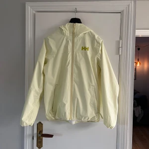 Helly Hansen Vindjacka - Säljer min Helly Hansen vindjacka som är perfekt till våren. Den har lite små svarta fläckar som jag visar på bild. Jackan är storlek M men skulle säga att den passar S då den är liten i storlek. Mitt pris är 199kr. OBS! Den är inte vit.