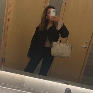 Beige handväska från Gucci - Säljer en snygg beige handväska från Gucci med det klassiska GG-mönstret. Väskan har två handtag och en dragkedja upptill. Perfekt för både vardag och fest! Tillkommer ett långt band så man kan ha den från axeln neråt. Äkta gucci väskan är vintage💗