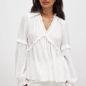 Vit blus med volangdetaljer - Säljer en superfin vit blus med volangdetaljer. Den har en v-ringad design och långa ärmar med volanger vid ärmslut och runt halsen. Perfekt för både vardag och fest! SUUPERSNYGG!! (Pris kommer vi överens om privat 🥰)