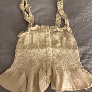 Beige topp - En väldigt  gullig beige topp som är använd ett par gånger. Den är i storlek 32 och är i god skick.