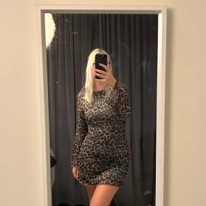 Leopardmönstrad klänning - Snygg leopardmönstrad klänning med långärmad design och öppen rygg. Perfekt för en djärv look. Klänningen är kort och har en tight passform som framhäver figuren.