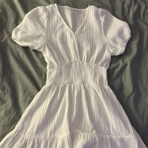 Vit klänning från Gina Tricot - Säljer en söt vit klänning från Gina Tricot med v-ringning och korta puffärmar. Klänningen har bara använt några få gånger. Säljer på grund av att den är för lite. Perfekt för sommaren!💗