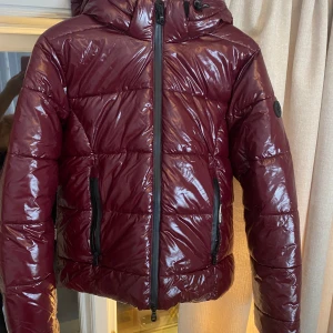 Vinröd vinterjacka Khujo - Säljer denna supersnygga vinterjacka ifrån märket Khujo. Väldigt sparsamt använd, i jättefint skick förutom ugglan man hänger upp jackan med gått av (bild 5). Liten i storleken. Nypris 2049kr.