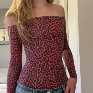 Leopardmönstrad offshoulder body - Snygg offshoulder topp med leopardmönster i svart och rött. Den är lite urtvättad vid sömmar vilket syns lite på tredje bilden.