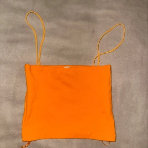 Orange ribbad tubtopp från Zara - Säljer en snygg orange ribbad tubtopp från Zara med smala axelband. Perfekt för sommardagar och kan enkelt matchas med olika outfits. Passar bra för en avslappnad stil.