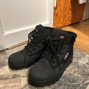 Svarta boots från Fila - Snygga svarta boots från Fila med snörning och robust sula. Perfekta för höst och vinter med en stilren design och bekväm passform. Använda extremt fåtal gånger!