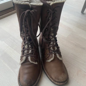 Bruna skinnstövlar med snörning - Snygga bruna stövlar i skinn med snörning och mysigt foder. Perfekta för kyligare dagar med sin robusta sula och varma insida. Storlek 38.