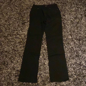 Svarta byxor med dragkedjedetaljer - Snygga svarta byxor med dragkedjor framtill. De har en bootcut-stil som ger en klassisk look. Perfekta för en stilren outfit.