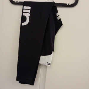 Aimn träningstights S - Snygga svarta leggings med vita detaljer och tryck. Perfekta för träning eller en avslappnad dag. De har en tight passform och är gjorda i ett stretchigt material för bästa komfort.