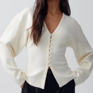 Vit kofta med knappar - !INTRESSEKOLL! stilren vit kofta med knappar framtill. Koftan har en v-ringad design och långa ärmar, perfekt för en elegant och avslappnad look. Tryck inte på ”köp nu” !kommer inte gå ner i pris då den är helt ny!