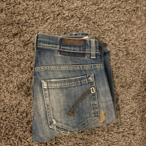 Dondup jeans  - Snygga blå jeans från dondup med slitna detaljer och en klassisk femficksdesign. De har en dragkedja och knapp framtill. Perfekta för en avslappnad stil.