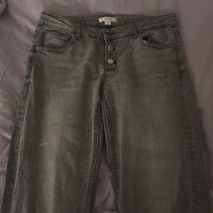 Grå jeans med bootcut - Snygga grå jeans med bootcut-stil. De har en klassisk femficksdesign och stängs med knappar framtill. Perfekta för en avslappnad look. Dom är i 170 tall, säljer då dom va för stora.