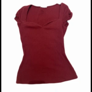 Vinröd Anna field topp  - Snygg vinröd ribbad topp från Anna Field med korta ärmar och en kroppad passform. Toppen har en  v-ringning och är tillverkad i ett mjukt material.💓 skriv om ni har några fler frågor eller vill ha fler bilder!